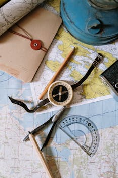 Flat lay of vintage compass, protractor, and maps for navigation study.
