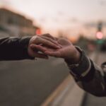 Nykyinen kuva: A tender moment as a couple holds hands on a street at twilight.